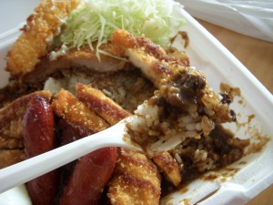 The curry is a deep brown color and full of pork bits