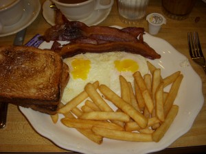 Two eggs over easy, bacon, french fries, and toast