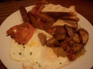 Eggs over easy with bacon, sausage, toast, and home fries