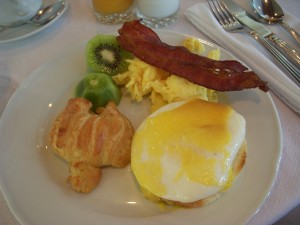 Eggs benedict, croissant, kiwi, scrambled eggs, bacon