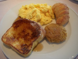 French toast, scrambled eggs, croissant, and some sort of fritter