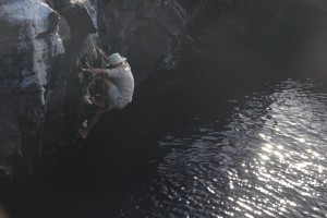 Naturalist climbing down the rocks to retrieve a hat