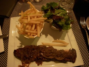 Hanger steak covered in carmelized onions, fries, and salad