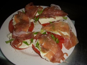 Fresh caprese salad topped with prosciutto